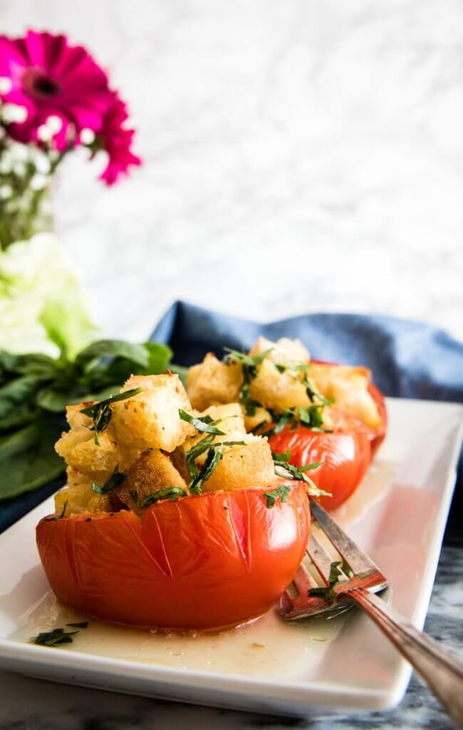 Egg-Stuffed Baked Tomatoes with Garlic Croutons with silver fork on a white plate.